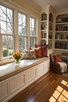 a window seat with bookshelves and pillows on it in front of two windows