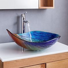a glass bowl sink sitting on top of a white counter next to a wooden cabinet