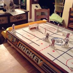 a cat sitting on top of a table next to an air hockey game in a living room