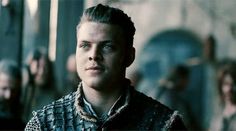 a man in a black and white shirt standing next to other people