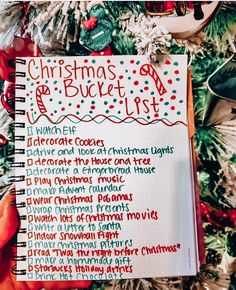 a christmas bucket list is shown in front of a christmas tree with ornaments and decorations