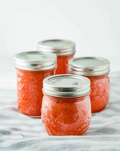four jars filled with orange colored food on top of a white and gray table cloth