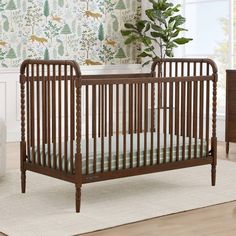 a baby crib in front of a wallpapered room with a potted plant