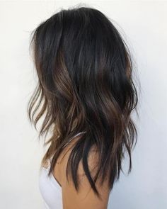 the back of a woman's head with long, wavy hair and brown highlights