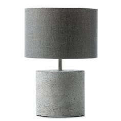 a lamp that is sitting on top of a table next to a white wall with a gray shade