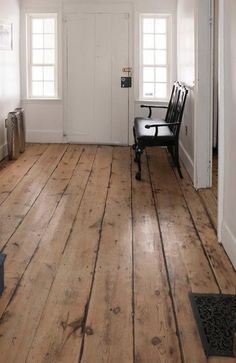 an empty room with white walls and wooden floors, two chairs on either side of the door