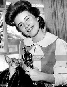 an old black and white photo of a woman holding a cat in her lap while smiling at the camera