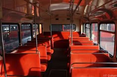 an empty bus with red seats is shown in this image, it's bright and sunny