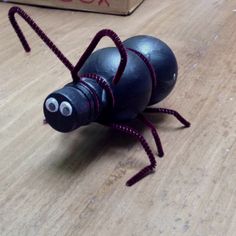 a black bug sitting on top of a wooden table next to a box with writing on it