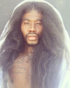 a man with long hair and tattoos on his chest wearing a white hood over his head