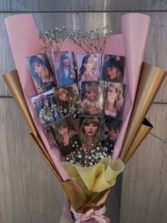 a bouquet of flowers with pictures on the front and side, wrapped in pink paper