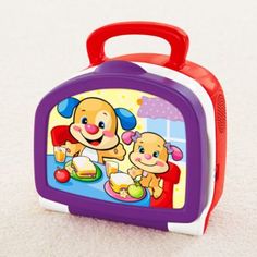 a purple and red lunchbox with a cartoon dog on it's side sitting on the floor