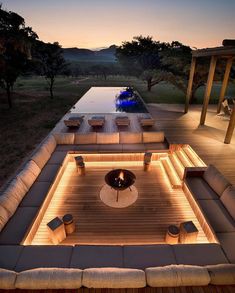 an outdoor living area with couches, tables and lights on the side of it