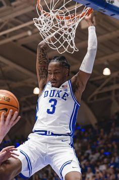 a basketball player dunks the ball in front of his opponent during a game at duke's