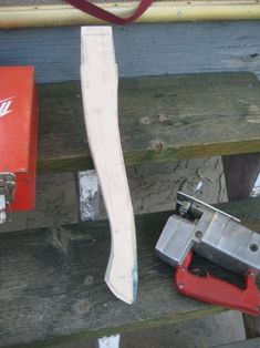 a red tool is sitting on a wooden bench