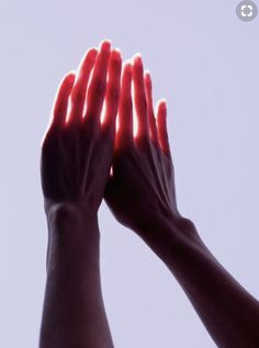 two hands reaching up into the air with red light coming from their fingertipss in front of them
