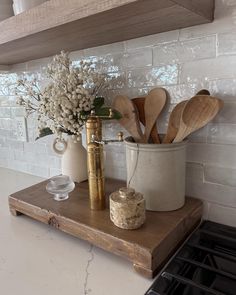 kitchen utensils and wooden spoons are sitting on a shelf in front of the stove