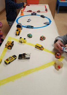 two children playing with toy cars on a table