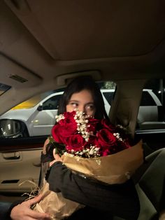 a woman sitting in the back seat of a car with flowers wrapped around her neck