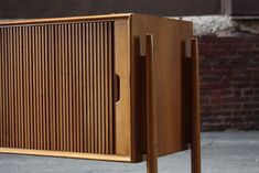 a wooden cabinet sitting on top of a sidewalk next to a brick wall and building
