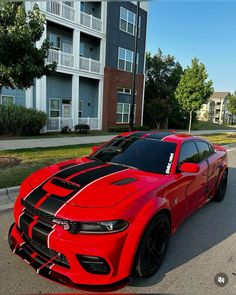 a red and black car parked in front of a building