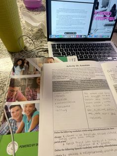 an open laptop computer sitting on top of a table next to a pile of papers
