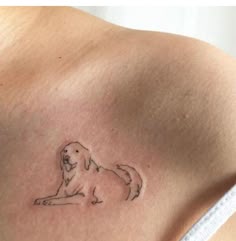 a small dog tattoo on the back of a woman's shoulder, with an outline of a dog
