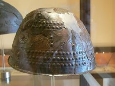 an old metal helmet on display in a glass case
