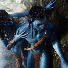 two people dressed as avatars standing next to each other in front of a cave