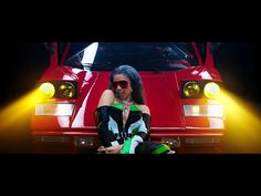 a woman sitting in front of a red sports car with yellow lights on her head
