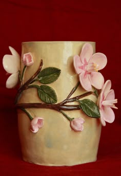 a ceramic vase with pink flowers and green leaves