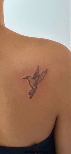 the back of a woman's shoulder with a bird tattoo on it