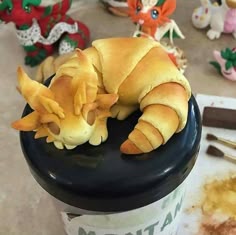 a croissant is sitting on top of a cup with paint and other toys in the background