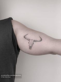 a man's arm with a bull skull tattoo on it