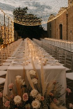 the tables are set up with white linens and flowers on them for an elegant dinner