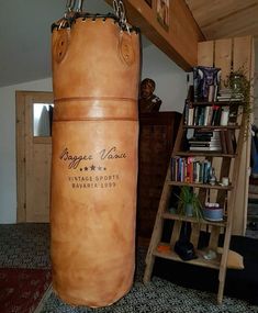 a large punching bag sitting on top of a carpeted floor next to a book shelf