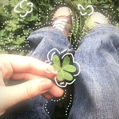 someone is holding a four leaf clover in front of their feet, with hearts on the grass behind them