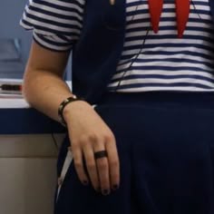 a woman in striped shirt and blue skirt with red bow on her neck sitting at counter