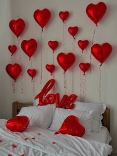 a bed with lots of red heart balloons on it