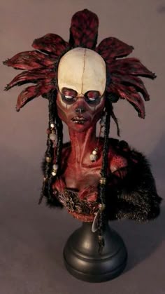 a creepy doll with long hair and red makeup on top of a black base stand