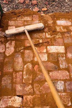 a baseball bat laying on the ground next to some dirt and brick bricks with a wooden stick sticking out of it