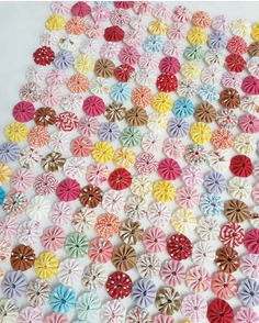 a large group of colorful paper flowers on a white tablecloth with polka dot dots