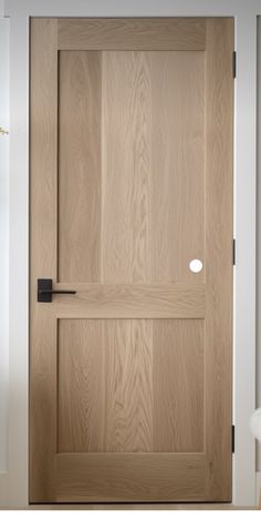 a wooden door with a black handle on the front and side panel, in an empty room