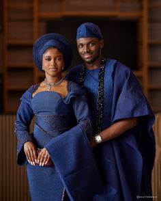 a man and woman standing next to each other in blue outfits with beads on their necklaces