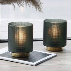 two candles sitting on top of a table next to a window