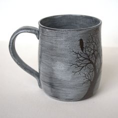 a black and white mug with a bird sitting on it's tree branch in the middle