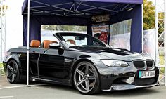 a black convertible car parked in front of a tent
