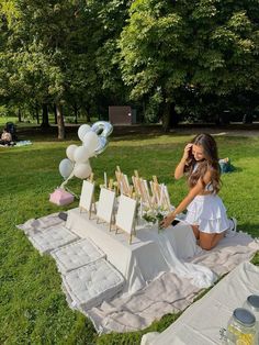 a woman sitting on the ground next to an easel with balloons and other decorations
