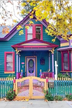 a blue house with red shutters and a yellow picket fence in front of it