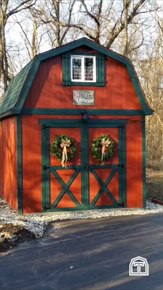 a red and green barn with wreaths on the doors